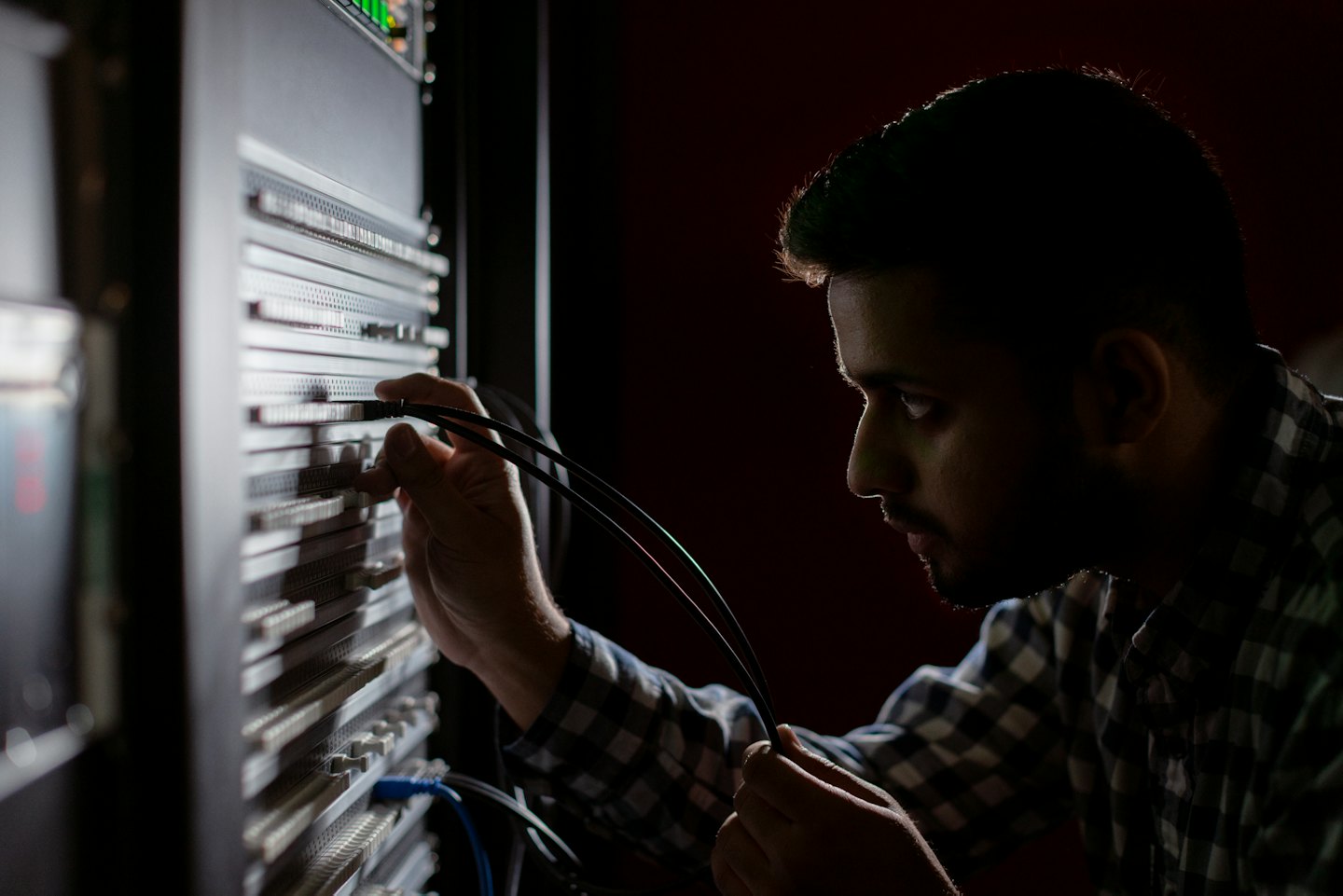 Hombre conectando cables a un rack de servidores en un centro de datos.